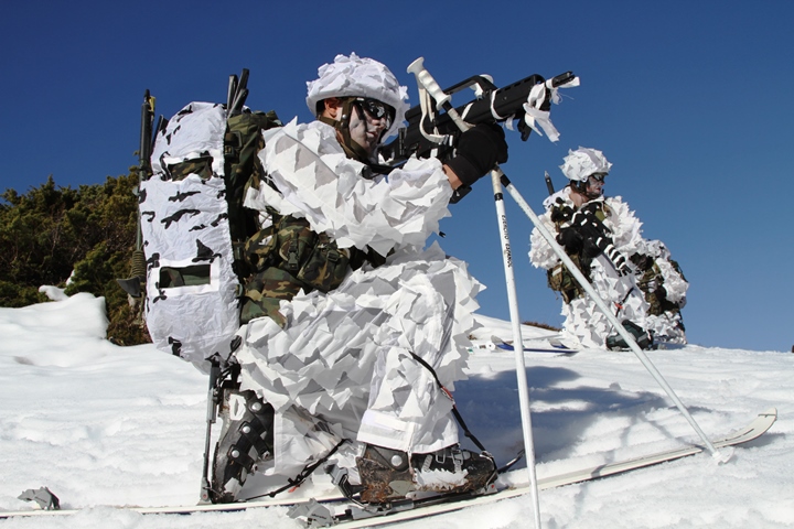 Cazadores de montaña con camuflaje blanco y esquís en terreno nevado